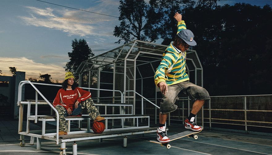 Model wearing a yellow green striped hoodie and long denim shorts at a skate court