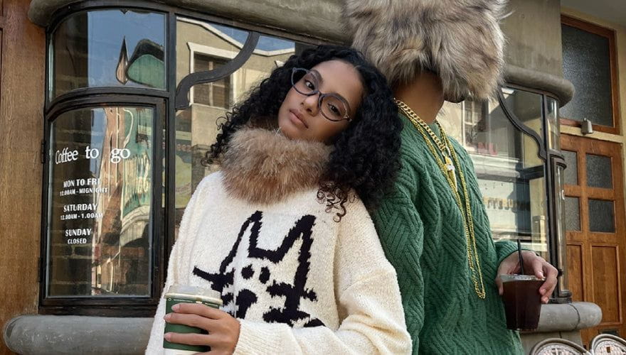 Model styling a patterned fur collar knit with green cable knit layers